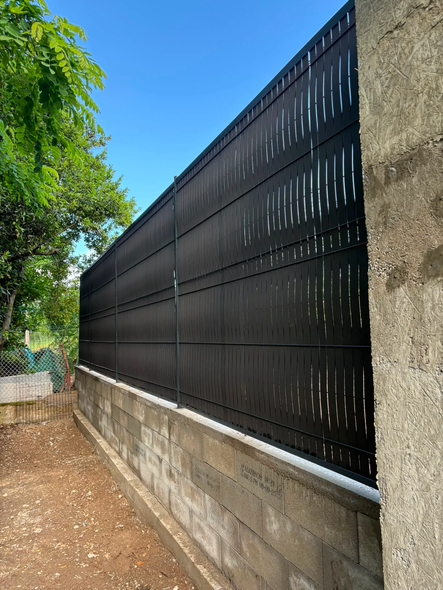 Clôture occultante noire posée sur un muret par Jardélie pour aménager un espace extérieur