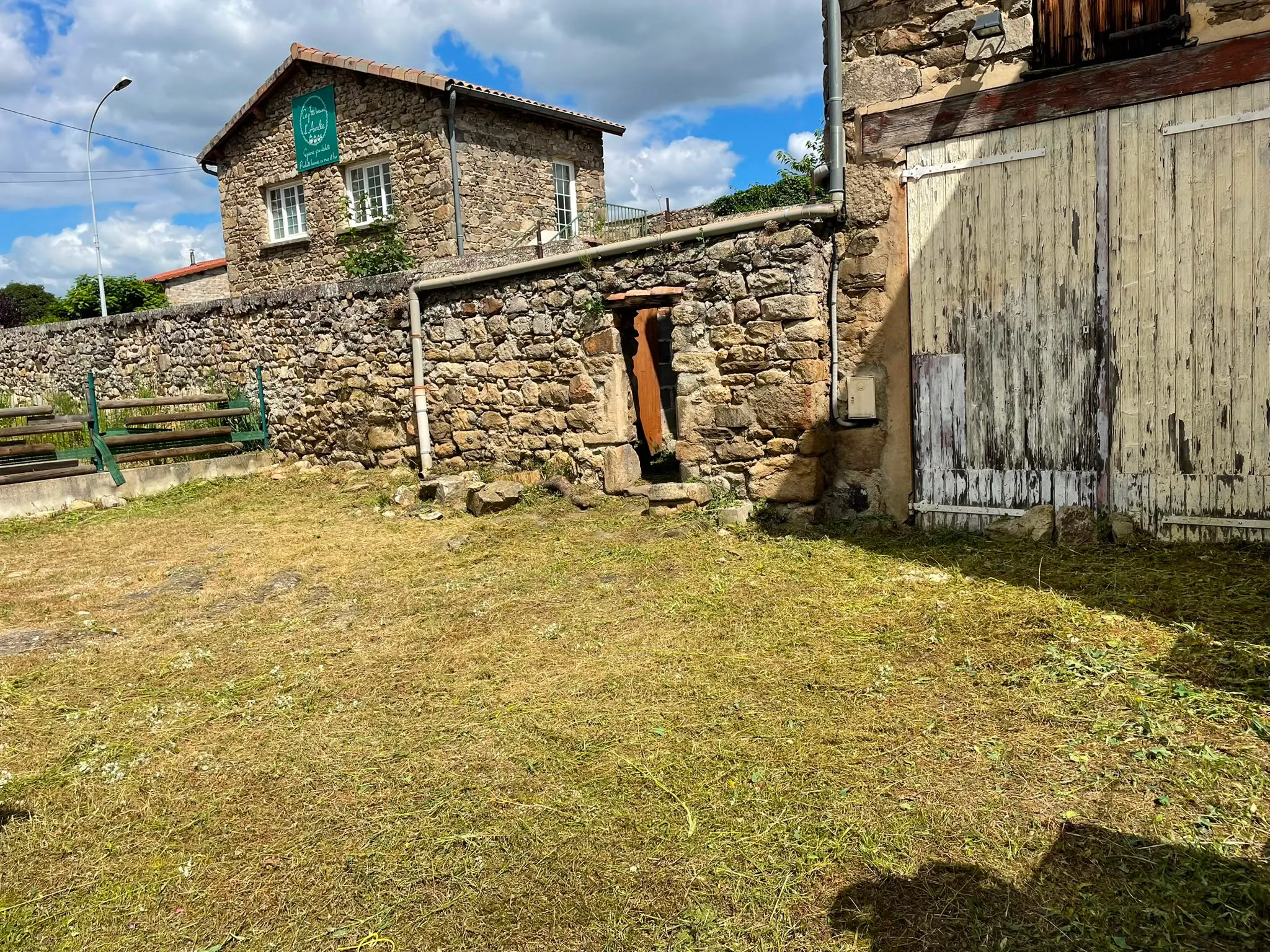 Terrain remis au propre après débroussaillage par Jardélie autour d’un bâtiment en pierre